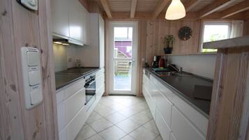 A kitchen with wooden walls, white cabinets, a stove, and a sink.