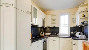 A modern kitchen with white cabinets, a black countertop, and a window providing natural light.