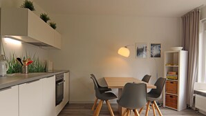 Eine moderne Küche mit Essbereich, Holzschränken, einem eingebauten Backofen und einem Esstisch mit Stühlen.