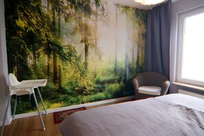 Egy hálószoba, melynek egyik falán nagyméretű, erdőt ábrázoló falfestmény látható, a szobában található egy ágy, egy szék és egy ablak, melyet függönnyel lehet lefedni.