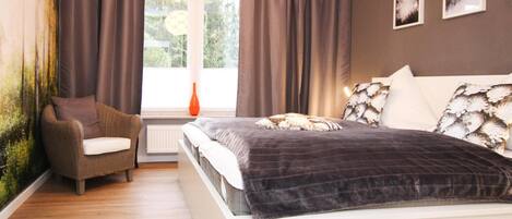 A bedroom with a bed, a chair, a window, and curtains.