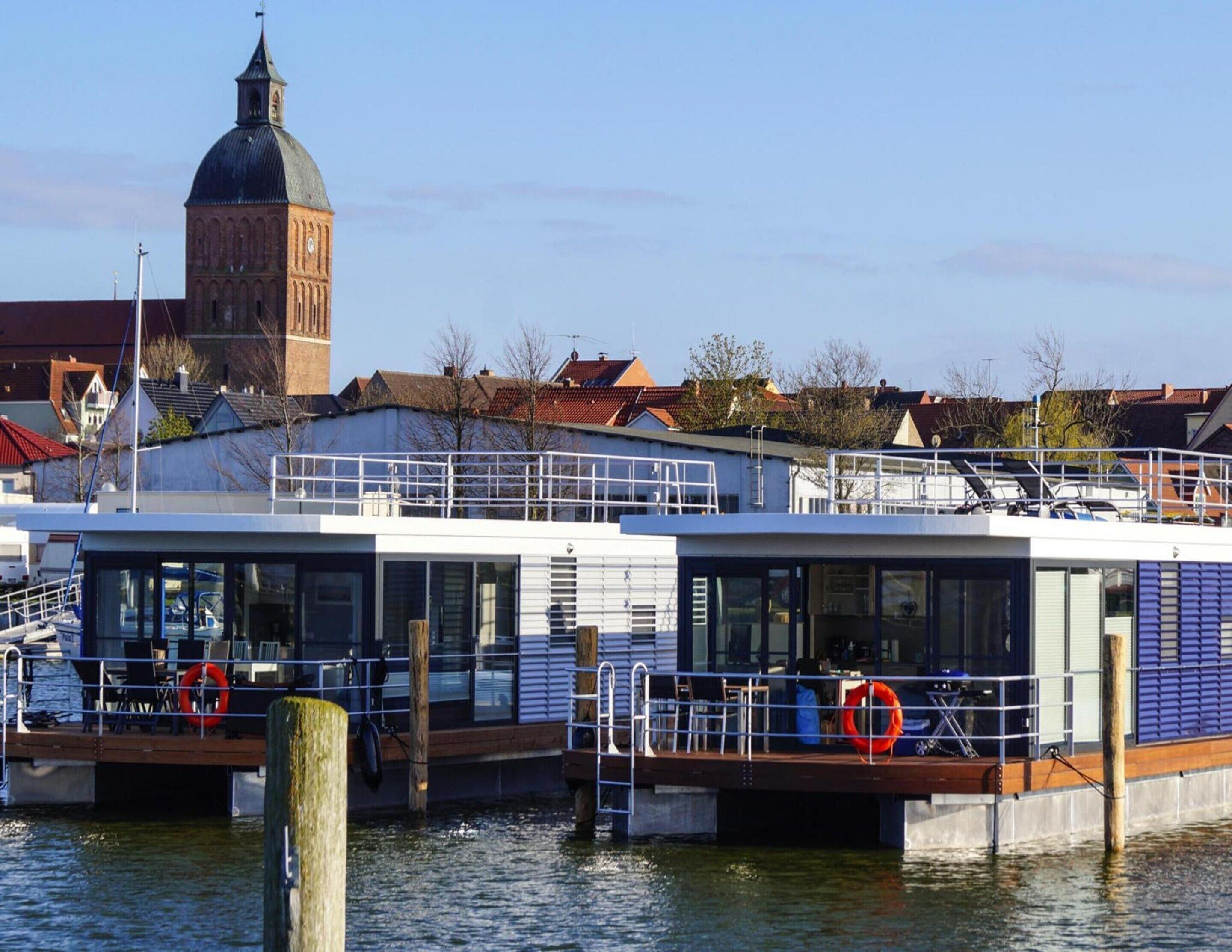 A modern boat docked at a pier with a historic building in the background.