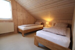 A small, wooden-paneled attic bedroom with two single beds, a nightstand, and a window. - Ferienhaus Seeidyll am Duemmer See, Duemmer (Dümmer)