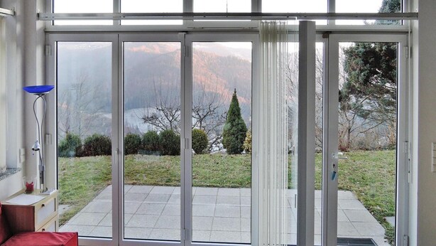 Une pièce dotée d’une grande porte-fenêtre coulissante qui donne sur un patio offrant une vue sur un paysage montagneux.
