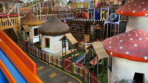Un espace de jeux pour enfants avec un toboggan, des cabanes et des structures colorées.
