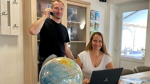Ein Zimmer mit Schreibtisch aus Holz, einem Globus und einem Laptop.