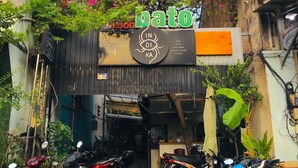A building with a sign reading "dato" and a signboard with "IN DI KA" and various services listed. There are motorcycles parked in front. - HoLo Bato SaiGon - Serviced HomeStay (Ho Chi Minh City)
