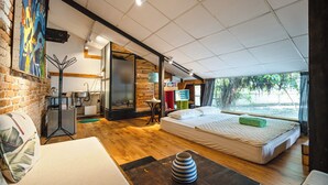 A modern hotel room with a large bed, a sofa, a coffee table, and a view of the outdoors. - HoLo Bato SaiGon - Serviced HomeStay (Ho Chi Minh City)