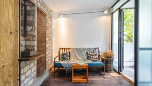 A cozy room with a wooden bench, a small table, and a basket. - HoLo Bato SaiGon - Serviced HomeStay (Ho Chi Minh City)
