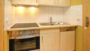 Una cocina compacta con horno integrado, estufa, fregadero y lavavajillas.