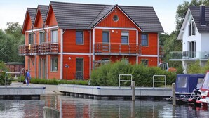 Una casa roja de varios pisos con balcones, un muelle y un bote.