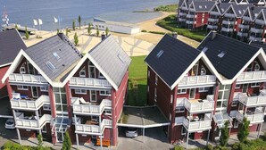 A coastal residential area with red and white buildings, balconies, and a beach in the background. - Vacation Park Muritz in Rechlin-nord (Rechlin)