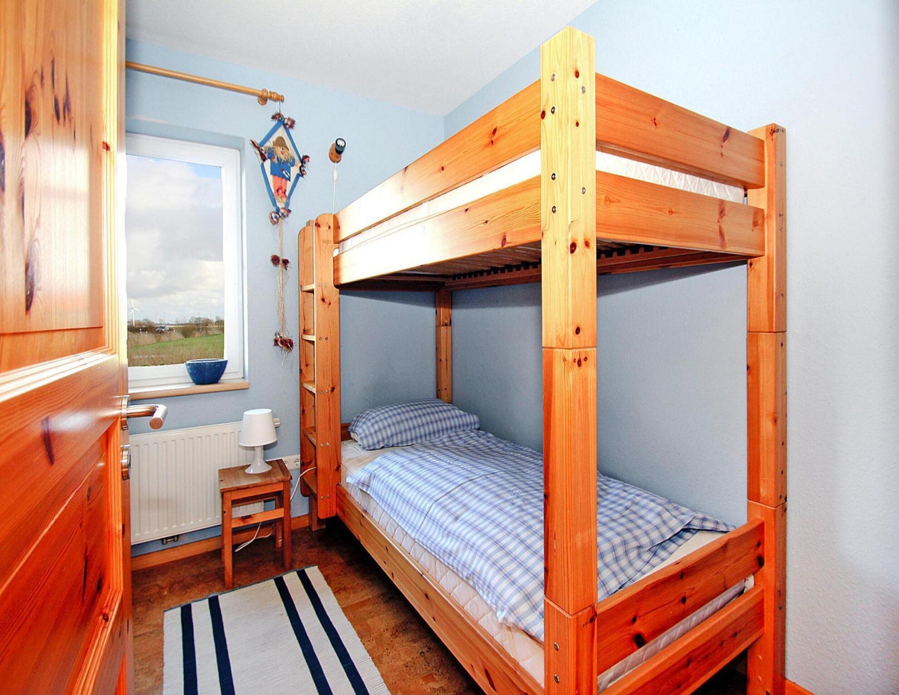 Une chambre avec un lit superposé, une fenêtre, un bureau et un radiateur.