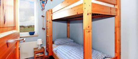 Une chambre avec un lit superposé, une fenêtre, un bureau et un radiateur.