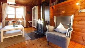 Ein gemütliches Blockhaus-Interieur mit Kamin, Esstisch und bequemen Sesseln.