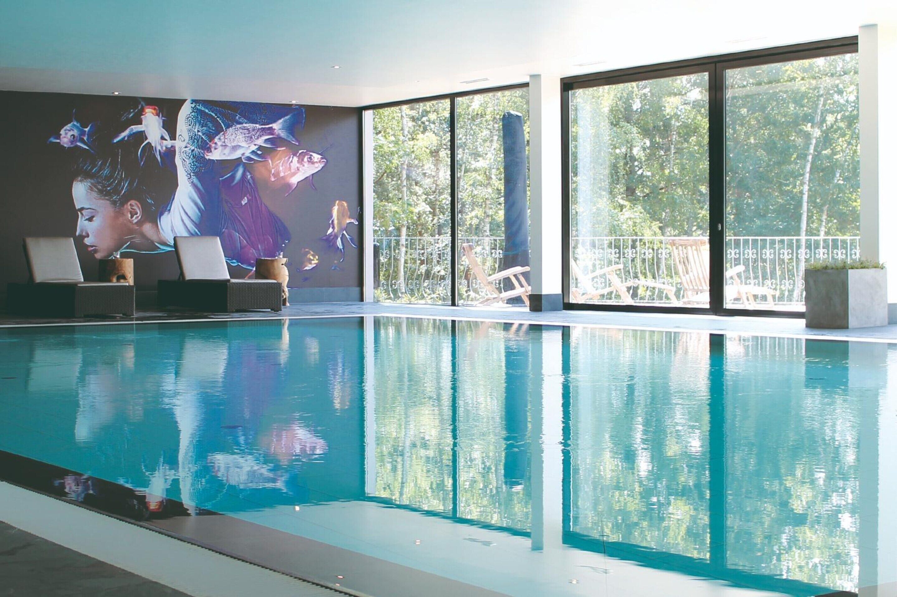 Une piscine intérieure à l’eau claire, une fresque représentant des poissons et de grandes fenêtres donnant sur l’extérieur.