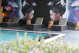 Un área de piscina con sillas de descanso, una computadora portátil sobre una silla y un cartel grande con diseño de pez.