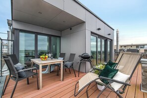 Une terrasse extérieure moderne avec une table en bois, des chaises et un barbecue.