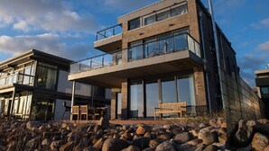A modern two-story building with large windows and a balcony. - Penthouse Dock 76 Bridge - waterfront location, roof terrace, sea view, sauna (Olpenitz)