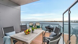 A deck with a table and chairs, a grill, and a view of the water. - Penthouse Dock 76 Bridge - waterfront location, roof terrace, sea view, sauna (Olpenitz)