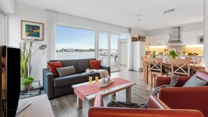 Ein modernes Wohnzimmer mit Sofa, Couchtisch und Essbereich mit Tisch und Stühlen.