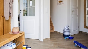 A hallway with a wooden bench, a hat, and a skateboard. - Luxushaus Boddenkuste mit Sauna (Fuhlendorf)