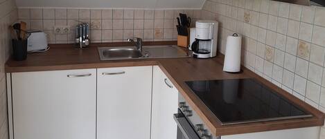 Pieni, käytännöllinen keittiö, jossa on pesuallas, kahvinkeitin ja liesi.