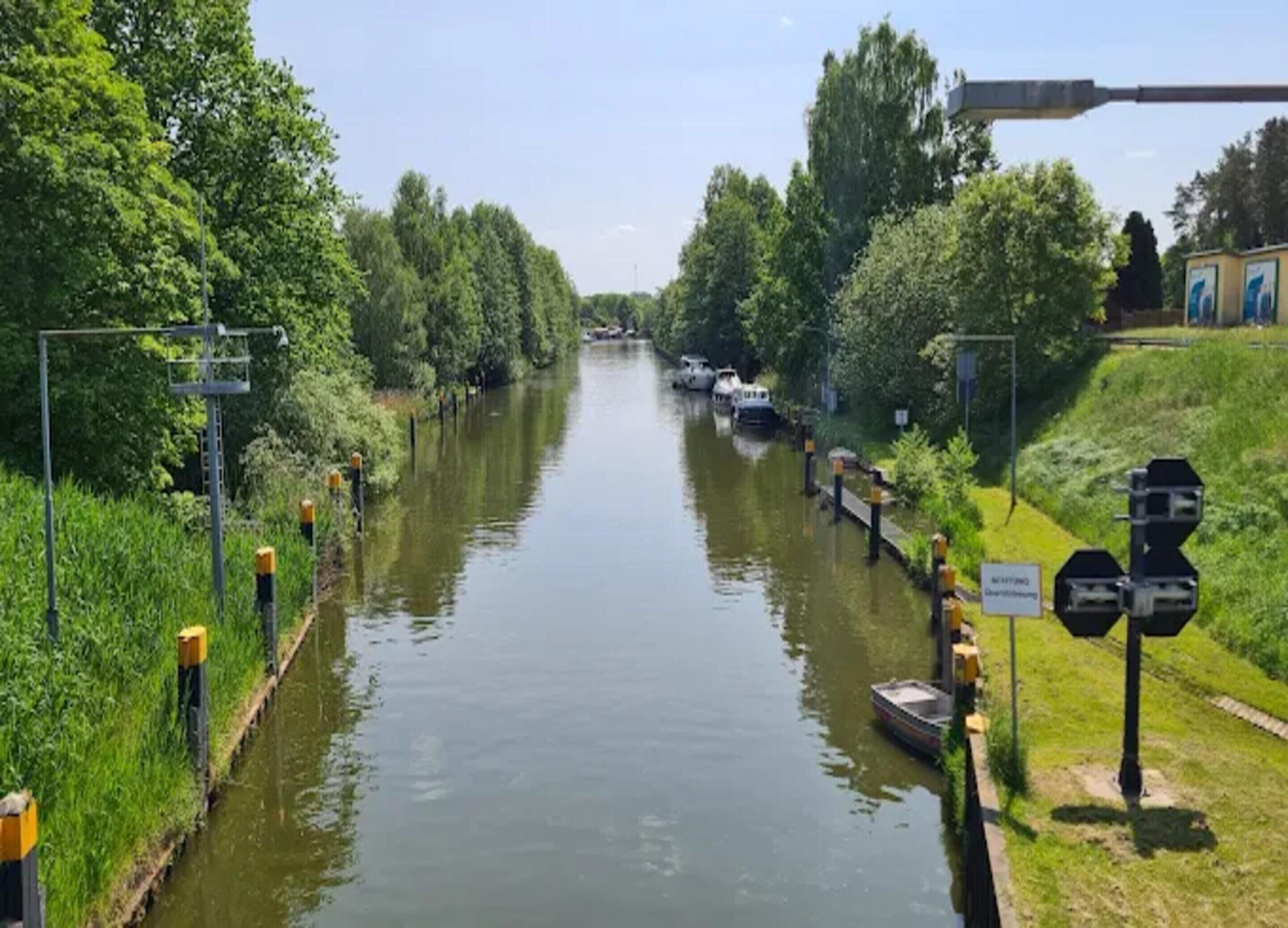 Un canal con barcos, rodeado de vegetación y un sendero peatonal.
