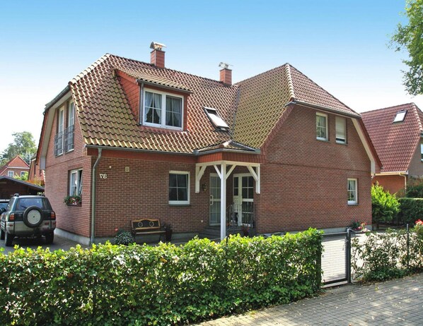 A two-story brick house with a sloped roof, a covered porch, and a fenced yard. - Ferienwohnungen am Mirower See, Mirow (Mirow)