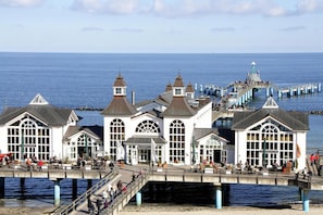 A waterfront building with multiple windows and a bridge leading to a pier. - Holiday Home Inselperle, Putbus (Putbus)