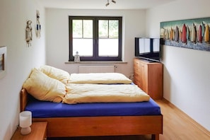 A bedroom with a bed, a window, a radiator, a television, and a painting on the wall. - Holiday Home Inselperle, Putbus (Putbus)