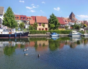 A calm canal with boats docked, surrounded by traditional European-style buildings with red roofs. - Appartement Hafenflair am Plauer See (Plau am See)