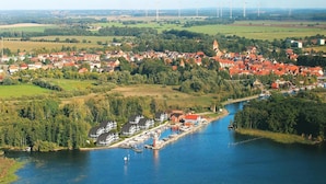 A riverside town with a marina, houses, and wind turbines in the background. - Appartement Hafenflair am Plauer See (Plau am See)