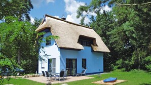 A blue house with a thatched roof, surrounded by greenery and trees. - Thatched House in Usedom Near Lagoon (Zirchow)