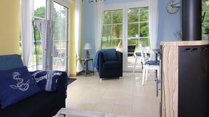 A living room with a sofa, a table, and a grill. - Thatched House in Usedom Near Lagoon (Zirchow)