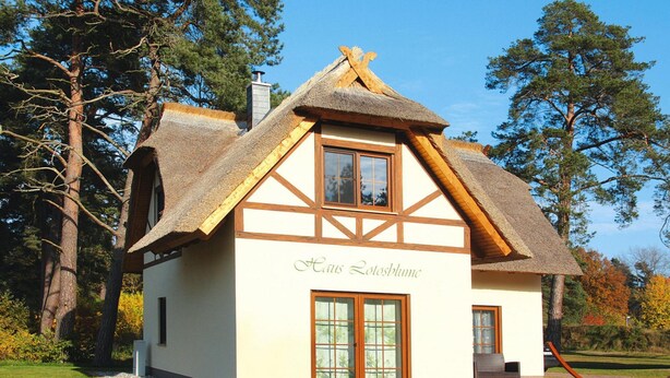 Ett traditionellt hus med ett halmtak, en träfasad och en skylt med texten ”Haus Lolosblume”.