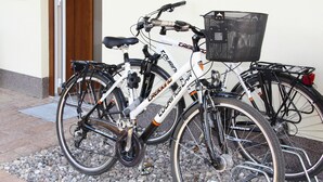 Två cyklar parkerade på en grusbelagd yta nära en byggnadsingång.