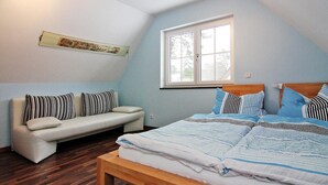 Ett sovrum med en säng, en soffa, ett fönster och en träbänk.