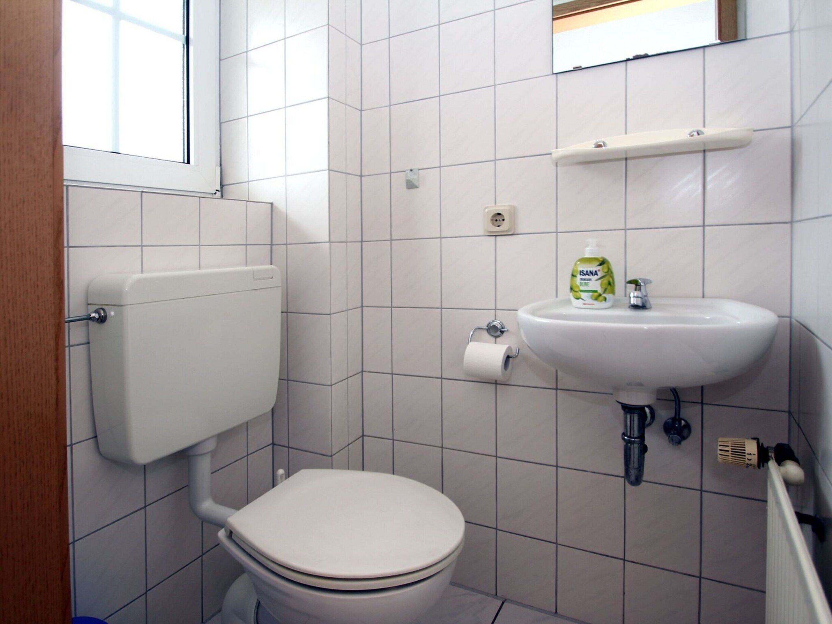 Ein kleines Badezimmer mit Toilette, Waschbecken und Fenster.