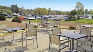 An outdoor patio with tables and chairs, overlooking a marina with boats and a lake. - Aparthotel by Lake Heidensee With Boat Rentals (Schwerin)