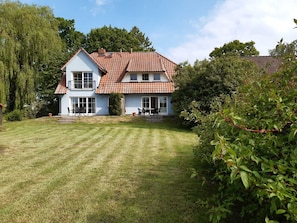 A two-story house with a tiled roof, a front porch, and a well-maintained lawn.