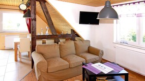 A cozy living room with a sofa, a coffee table, and a TV mounted on the wall. - Ferienwohnung Alte Schmiede, Zemitz (Zemitz)
