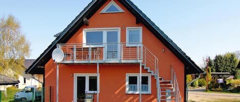 Kaksikerroksinen talo, jossa on parveke, satelliittiantenni ja portaat, jotka johtavat yläkertaan.