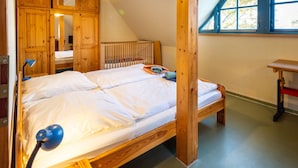 Une chambre avec un grand lit, des meubles en bois, un bureau et une fenêtre donnant sur la forêt.