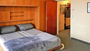 Un dormitorio con cama, armario de madera y un armario pequeño.