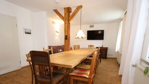 Una sala da pranzo con un tavolo e sedie in legno, una TV montata a parete e un termosifone.