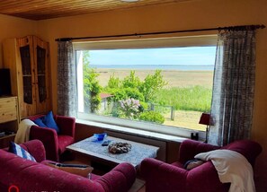 Ein Zimmer mit einem großen Fenster, einer Couch, einem Tisch und einem Fernseher.