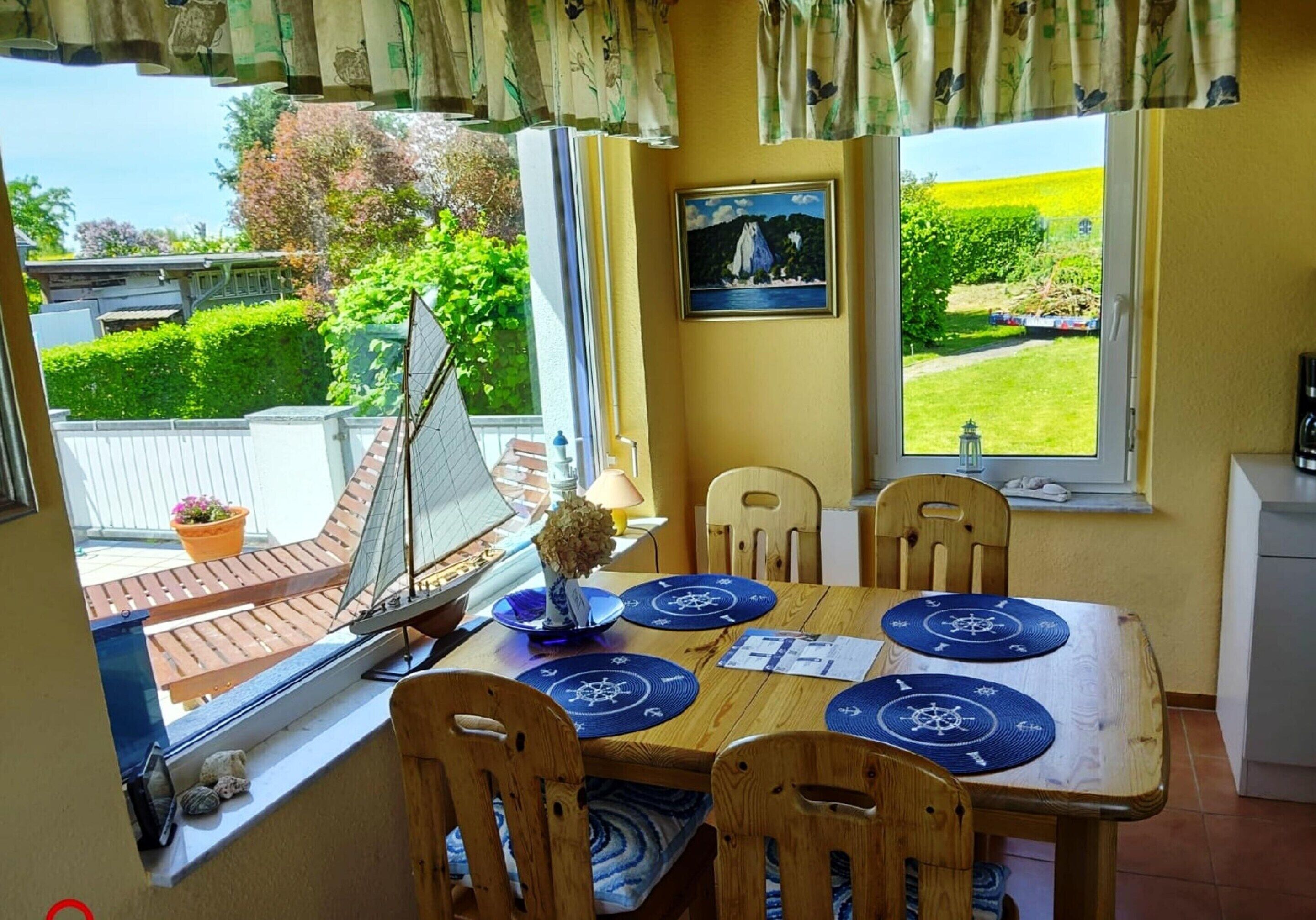 A dining area with a wooden table, blue placemats, and a sailboat model.