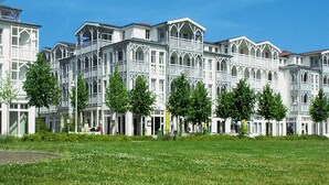 A large, white, multi-story building with a symmetrical facade, featuring numerous windows and balconies. - Ferienwohnungen im Seepark Sellin (Sellin)