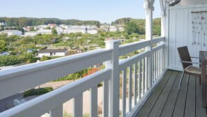 A balcony with a view of a town, white railing, and a wicker chair. - Ferienwohnungen im Seepark Sellin (Sellin)